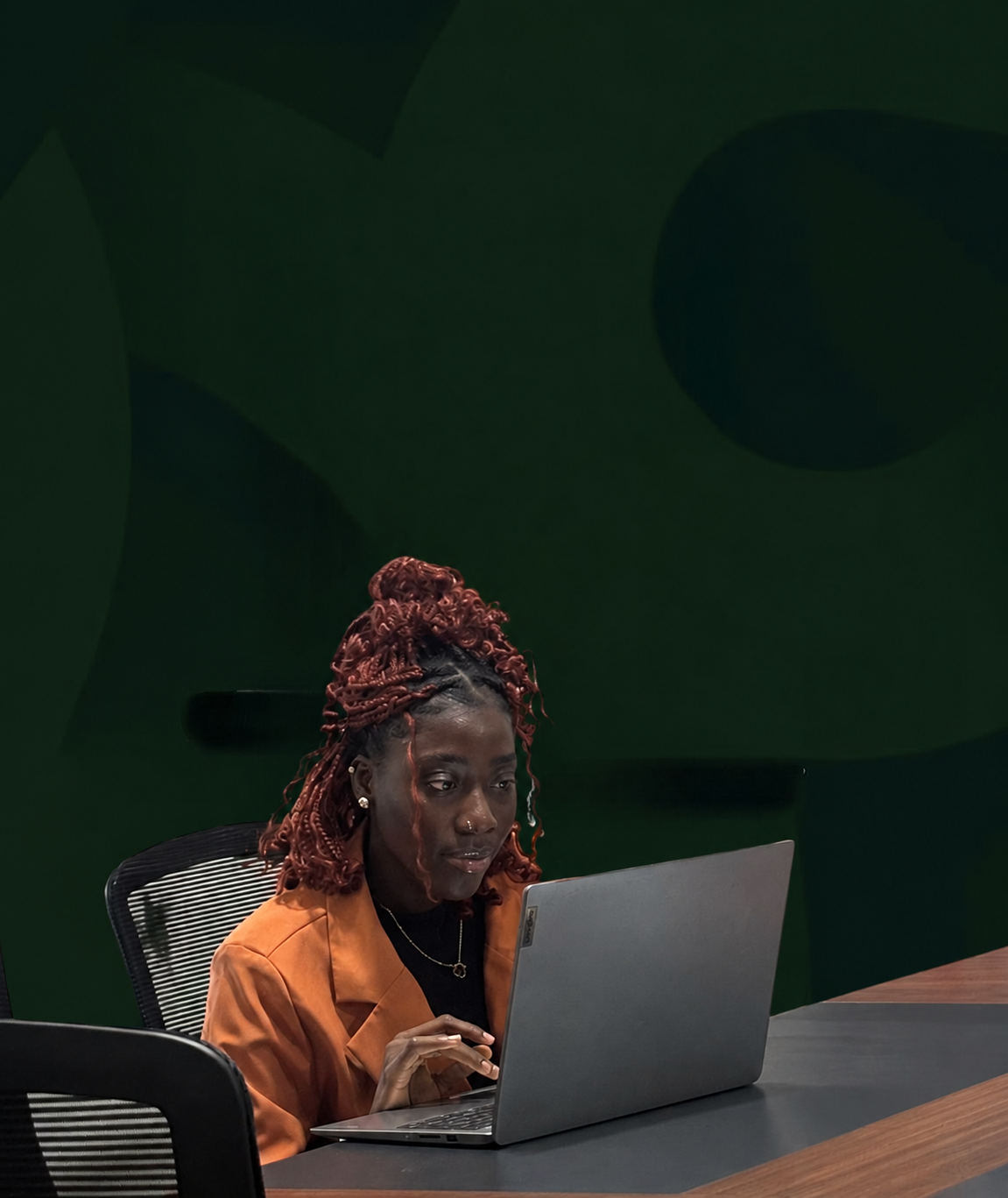 A woman working on a laptop at an office desk